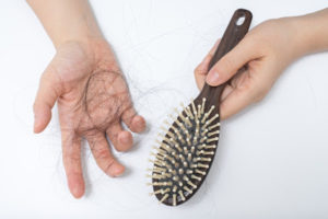 Hair loss in woman hands and bruch, on white background, women postpartum defluvium